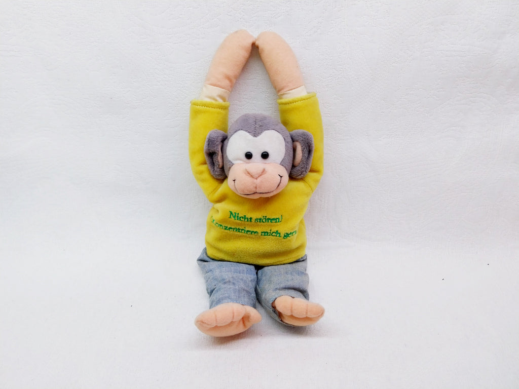 Plush monkey toy in yellow shirt and jeans with arms raised