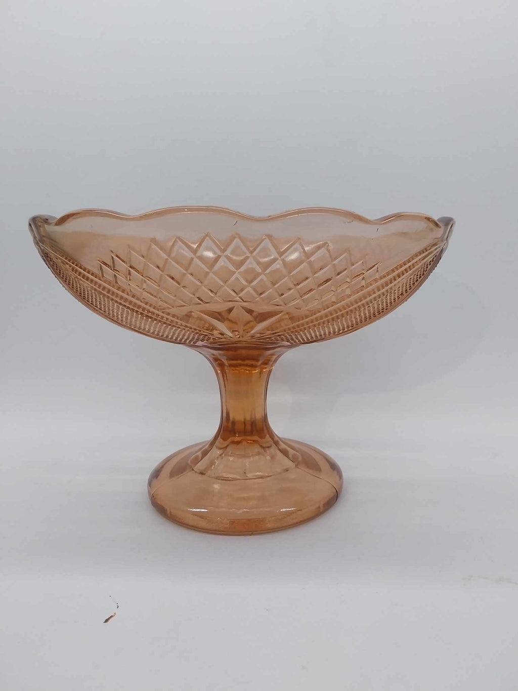 Vintage peach pink pressed glass compote with diamond pattern and scalloped rim on pedestal base