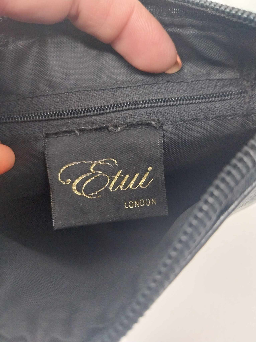 Interior of Etui London bag showing embroidered gold label and zip pocket lining