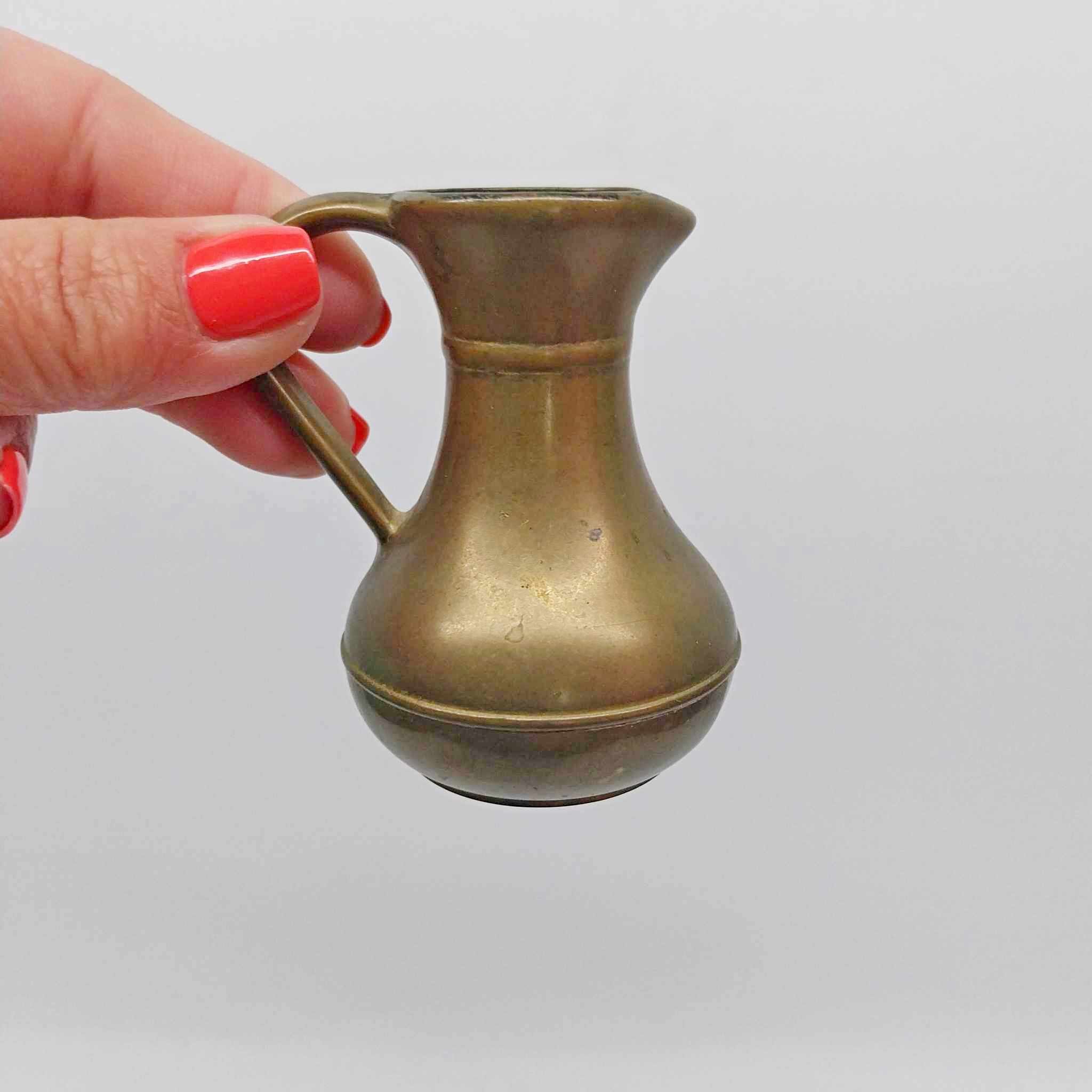 Miniature vintage brass pitcher vase held in hand