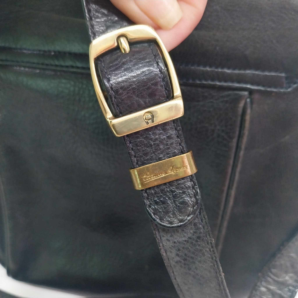 Close-up of Etienne Aigner gold-tone horseshoe buckle and engraved signature on leather strap