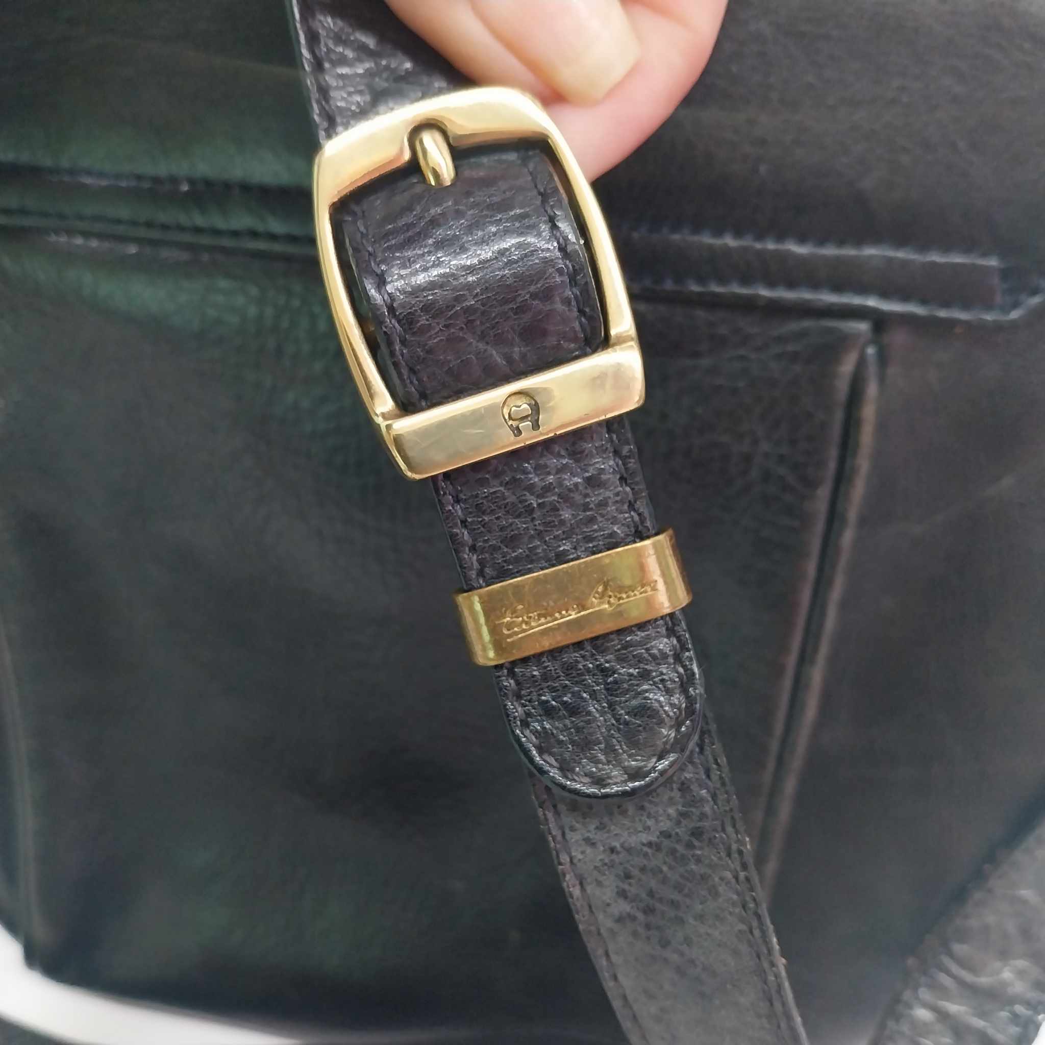 Close-up of Etienne Aigner gold-tone horseshoe buckle and engraved signature on leather strap