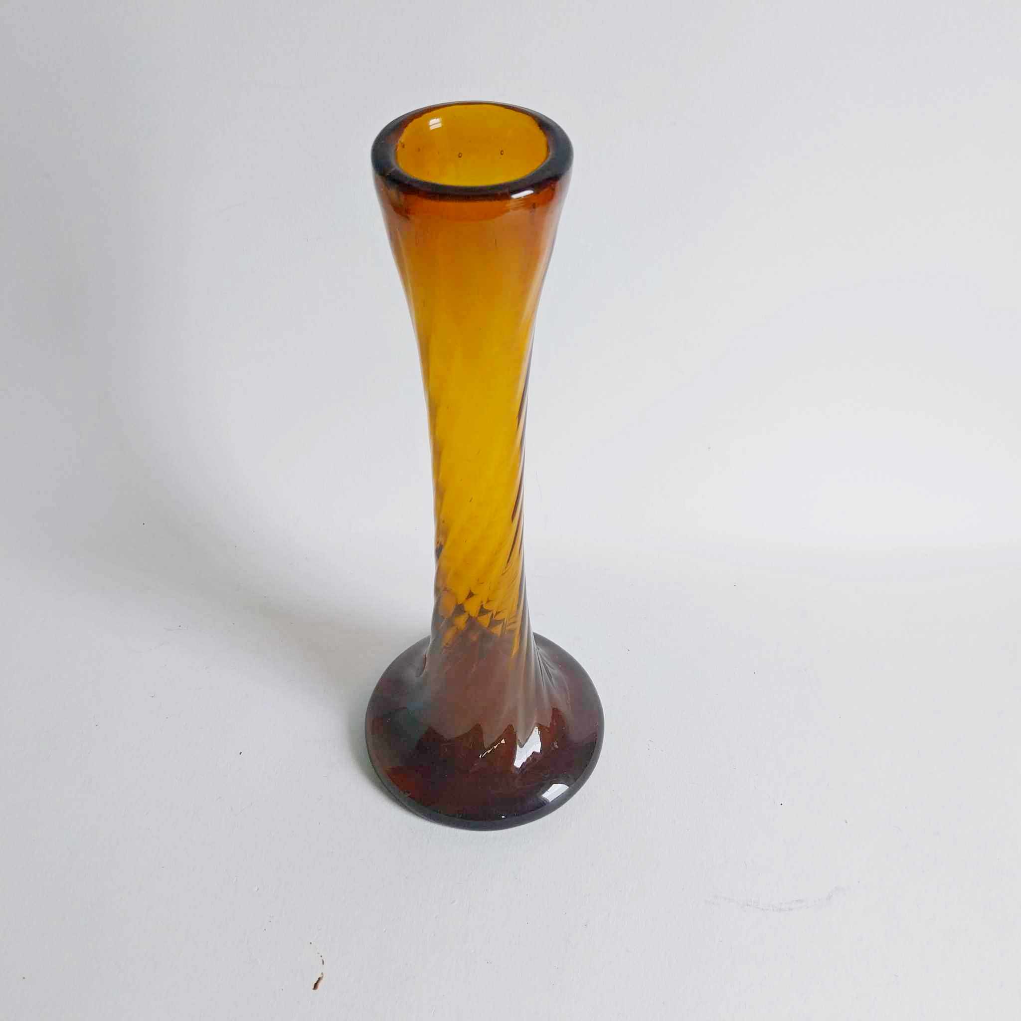 Vintage amber glass bud vase with twisted spiral neck and round base, glowing orange-gold colour
