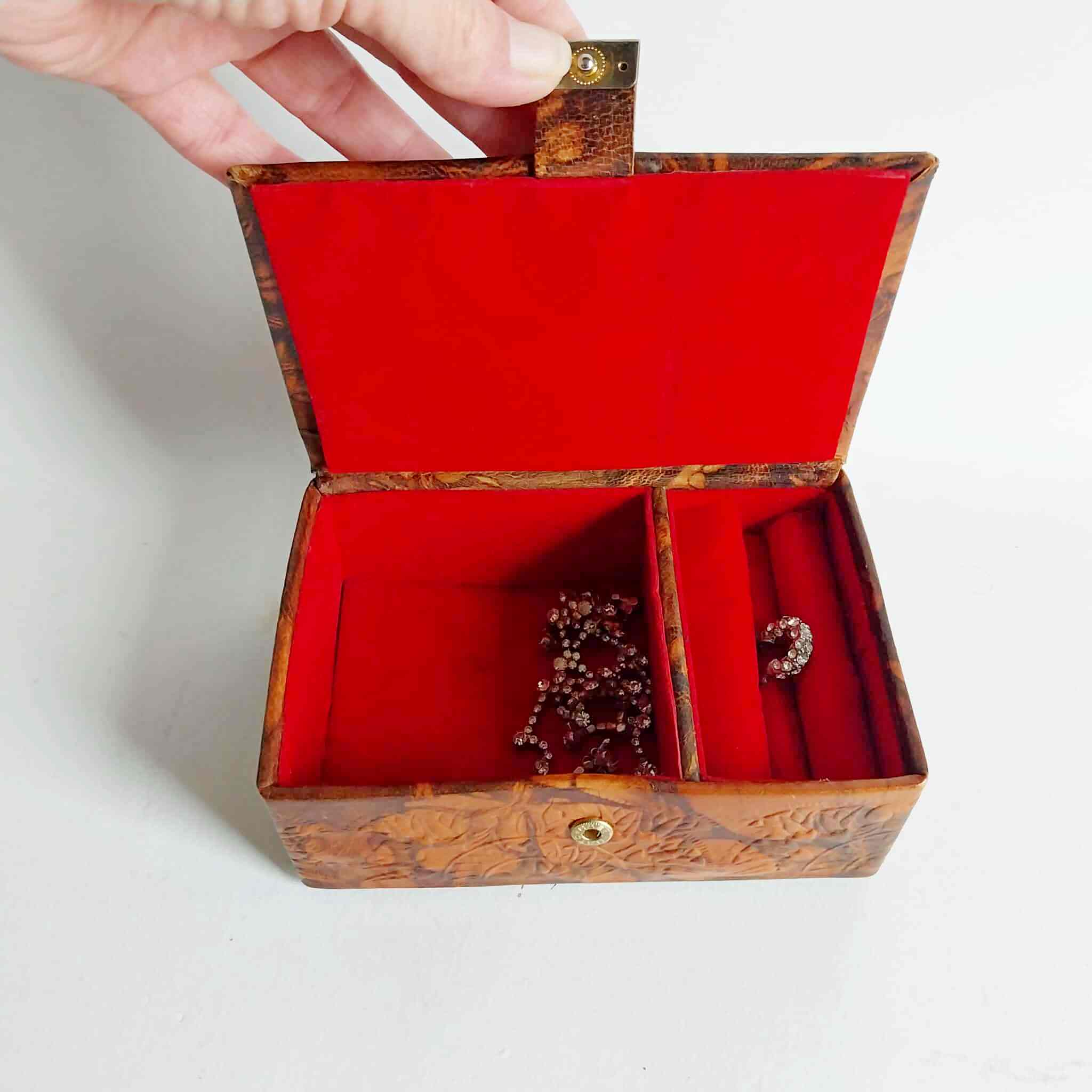 Interior of vintage jewelry box with red velvet lining and compartments