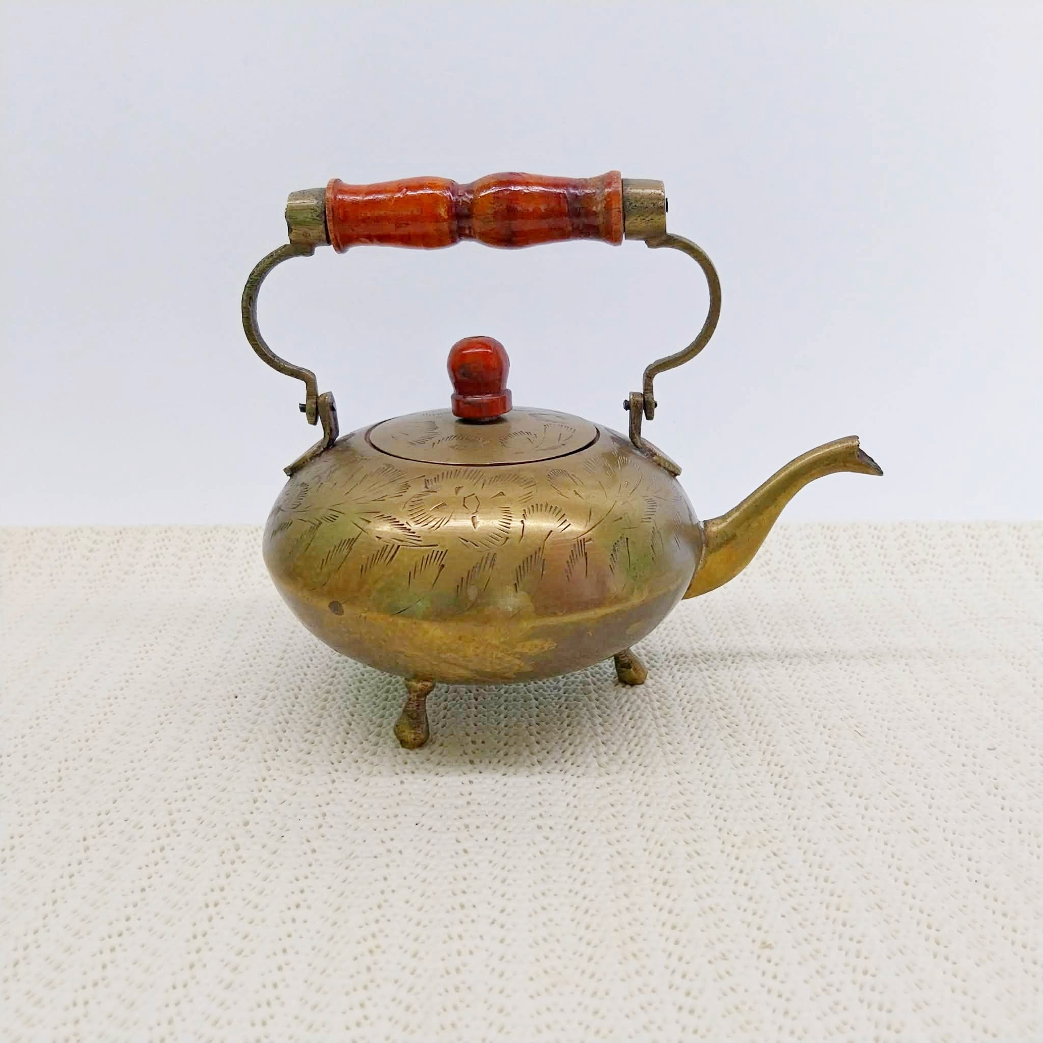 Vintage brass decorative teapot with wooden handle and engraved florals