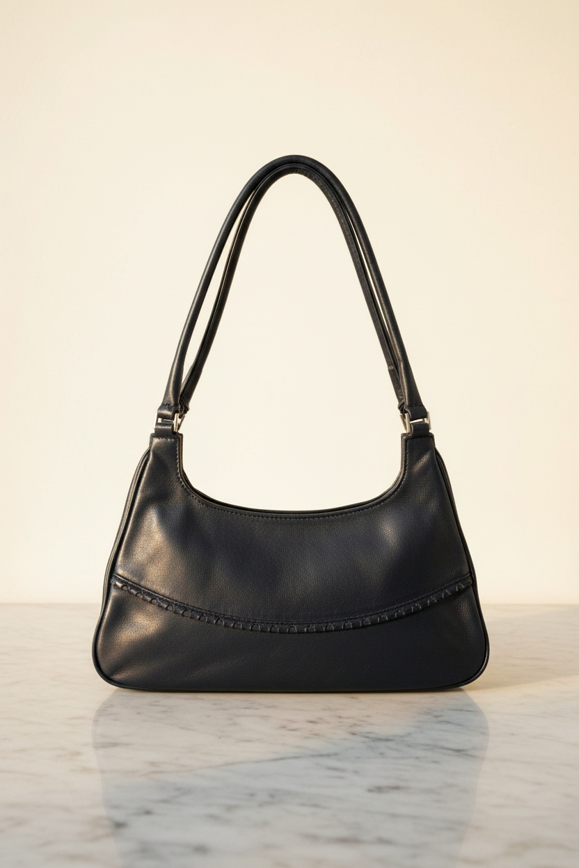 Vintage Moragaia navy blue leather shoulder bag with decorative curved seam, on marble surface