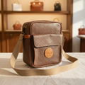 Vintage Bric's brown textured leather crossbody shoulder bag on cream linen with natural light