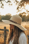 Vintage wide brim straw hat with wooden bead band worn on head, bohemian summer style