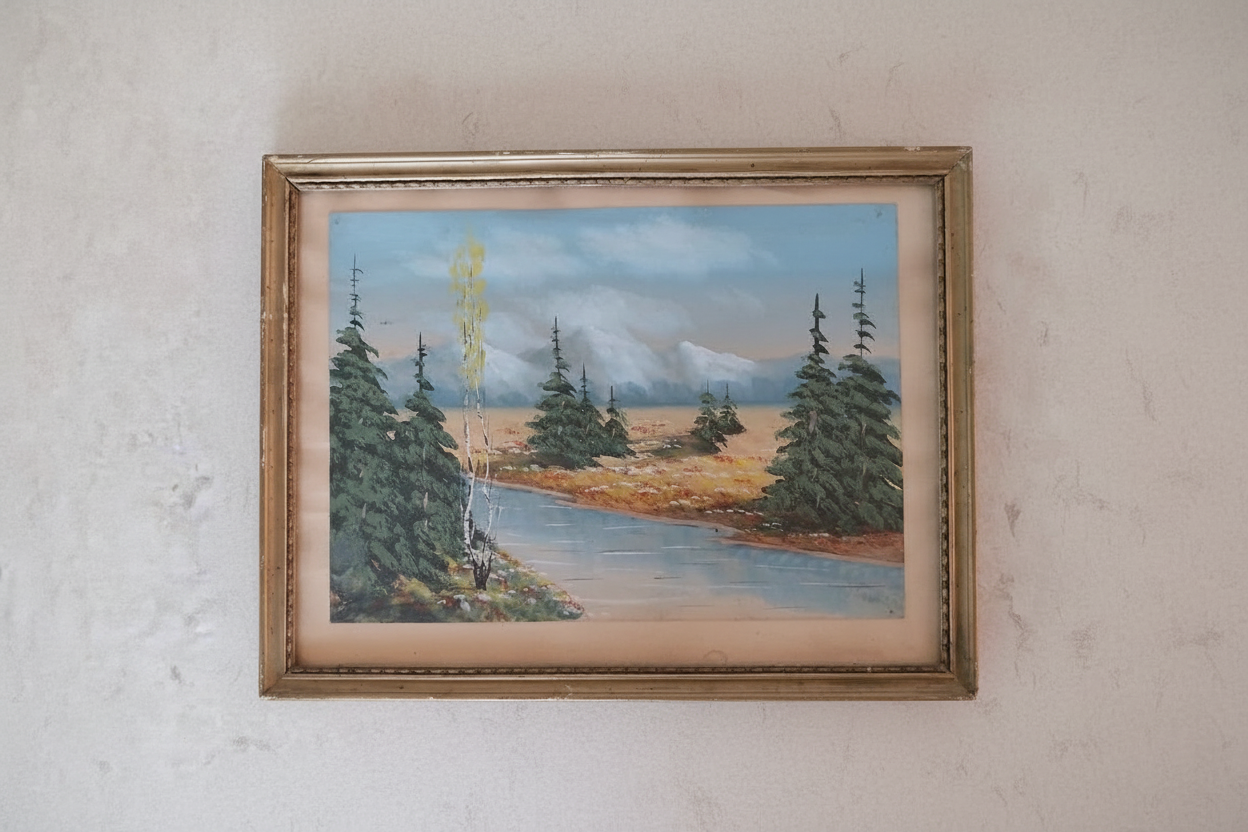 Vintage oil painting of autumn mountain landscape in gilded frame, centered on wall in natural daylight